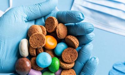 behandschuht Hände halten Süßigkeiten über medizinisches Material wie Masken